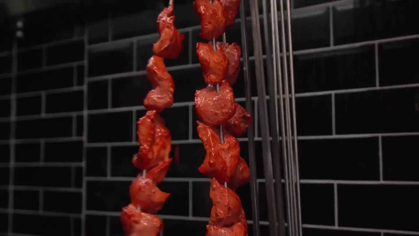 Küche des Royal Tandoor: marinierte Spieße hängen vor schwarzen Kacheln
